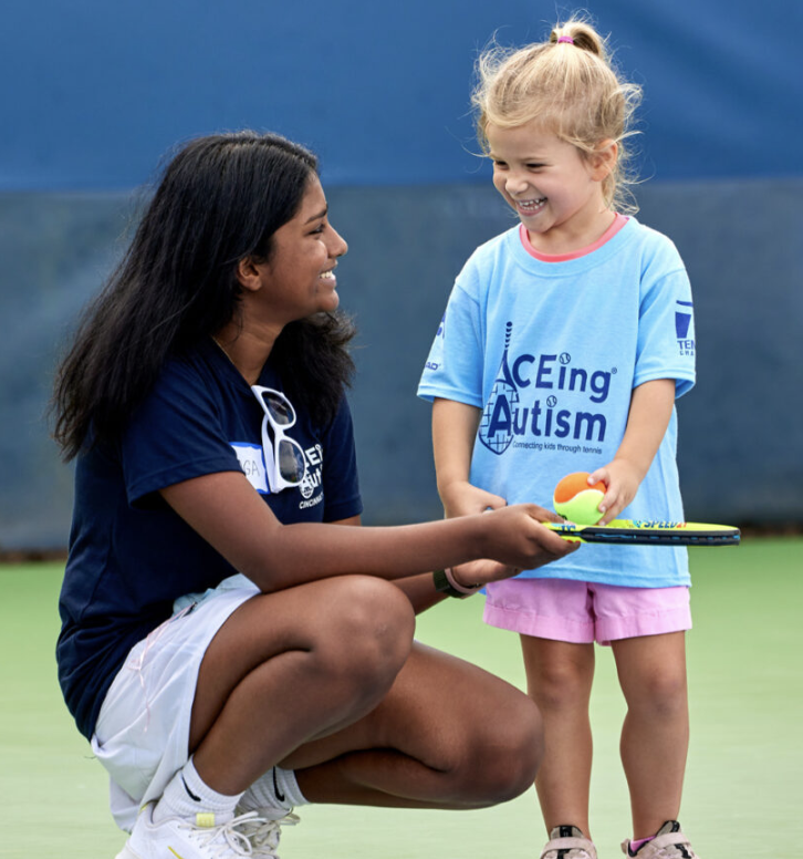 A BOOST volunteer and student participating in a tennis activity